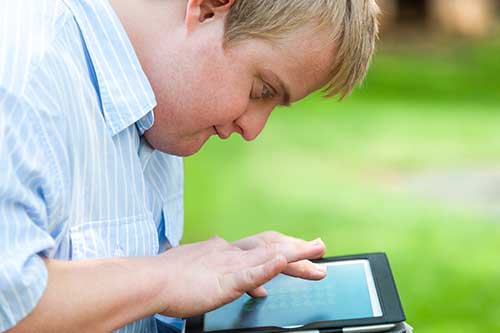 Teen with down syndrome using a tablet.