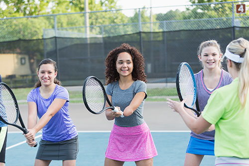 Girl-with-amputated-arm--playing-tennis with peers.