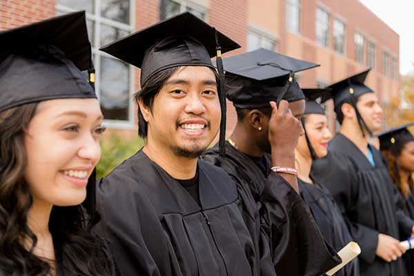 diverse group of teens their high school graduation wearing their black caps and gowns.