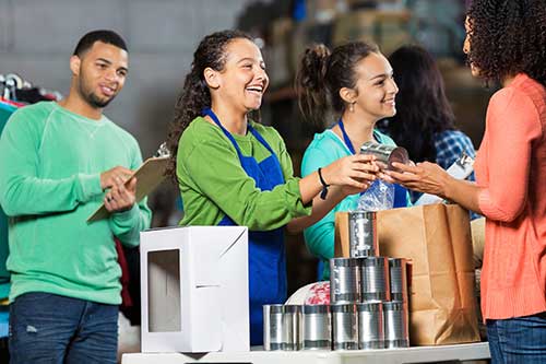 A group of teens handing out food at a food pantry.